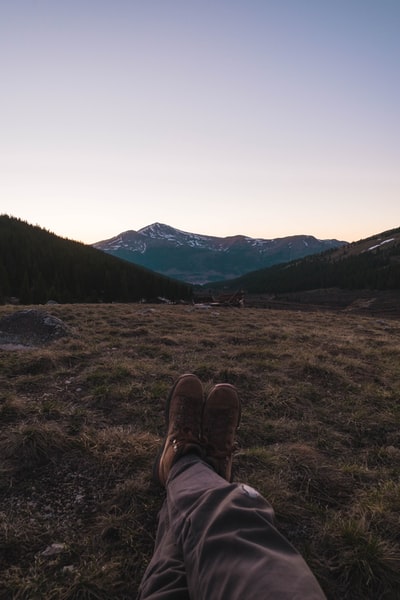 白天穿着棕色登山鞋坐在棕色草地上的人